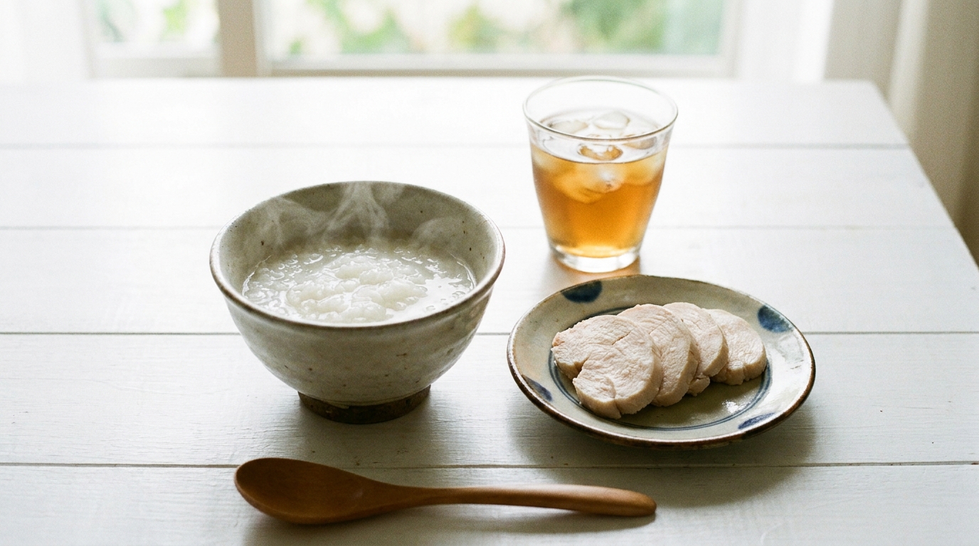 健康診断前日の推奨メニュー。おかゆ、サラダチキン、麦茶が並んだ清潔感のある食卓。